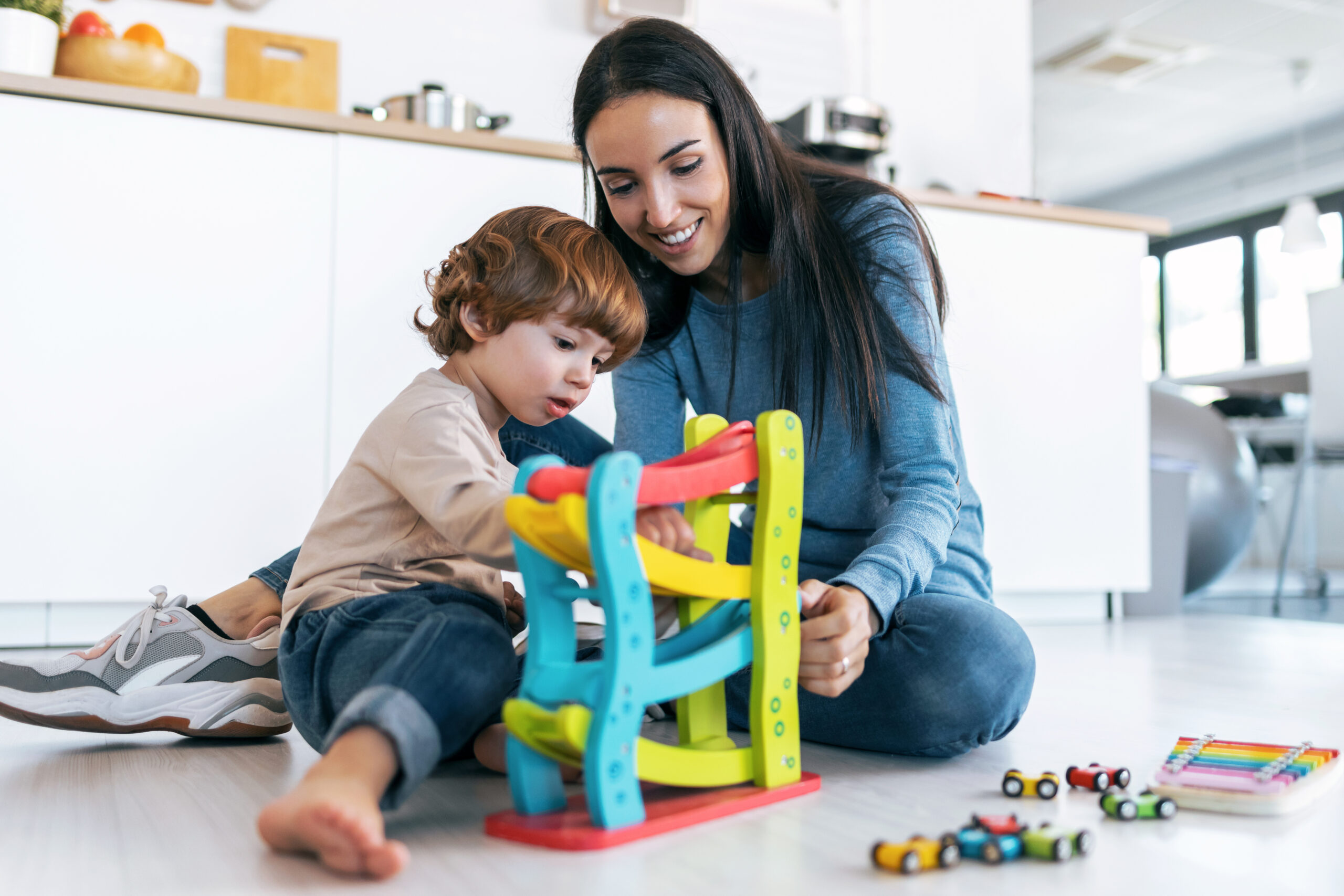 Shot of young beautiful mother playing on the floor with her son in living room at home.